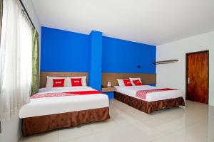 two beds in a room with blue walls at Collection O near Paris Van Java formerly Cassa Dua Hotel in Bandung