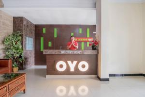 a woman is standing behind a reception desk in a lobby at Hotel O Medan Near Gajah Mada formerly Hotel Indah Raya in Medan