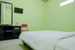 une chambre avec un lit, un miroir et une chaise dans l'établissement OYO Life 2508 Alba Suites Homestay Syariah, à Tulungagung