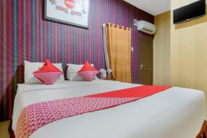 una camera da letto con un letto grande con cuscini rossi di Hotel O Medan near Balai Kota Lama formerly Hotel Labuhan Raya a Medan