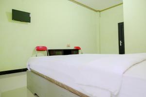 une chambre avec un lit blanc et deux chaises rouges dans l'établissement OYO Life 2508 Alba Suites Homestay Syariah, à Tulungagung