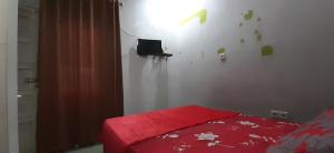 una camera con un letto con una coperta rossa e una TV di Hotel O Gurita Residence Syariah a Padang
