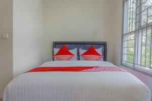 a white bed with red pillows in a bedroom at Hotel O 77 Guesthouse in Tjilandak +61 photos