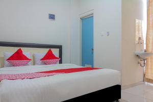 a bedroom with a large white bed with red pillows at Hotel O 77 Guesthouse in Tjilandak