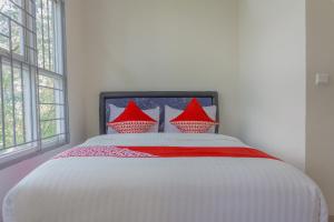 a bedroom with a white bed with red pillows at Hotel O 77 Guesthouse in Tjilandak