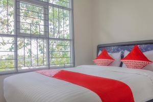 a bedroom with a red and white bed with windows at Hotel O 77 Guesthouse in Tjilandak