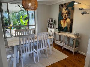 a dining room with a table and chairs and a painting at Frogs by the Sea in Cronulla