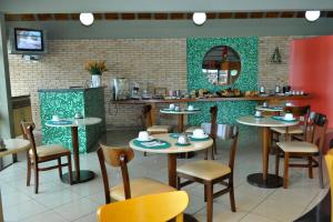a restaurant with tables and chairs and a mirror at Arcadas Hotel in Caçapava