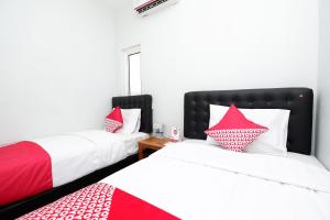 two beds in a room with red and white pillows at Hotel O Palebon Residence in Semarang