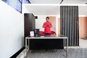 a man standing in front of a desk with a laptop at Hotel O Palebon Residence in Semarang