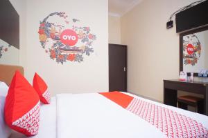 a bedroom with a white bed with red pillows at Hotel O near Universitas Widya Dharma formerly Nugraha Residence in Talang Kelapa