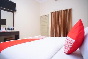 a bedroom with a bed with a red pillow at Hotel O near Universitas Widya Dharma formerly Nugraha Residence in Talang Kelapa