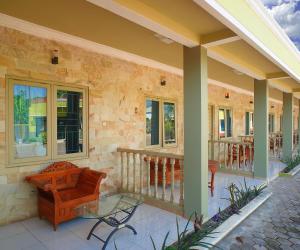 a porch of a house with a bench and a table at Hotel O near Universitas Widya Dharma formerly Nugraha Residence in Talang Kelapa +26 photos