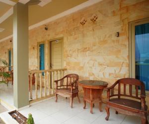 a patio with two chairs and a table on a porch at Hotel O near Universitas Widya Dharma formerly Nugraha Residence in Talang Kelapa