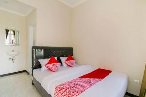a bedroom with a bed with red and white pillows at Hotel O Fakhira Residence in Tjiandjur