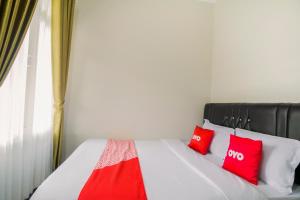 a bedroom with a bed with red pillows on it at Hotel O Fakhira Residence in Tjiandjur