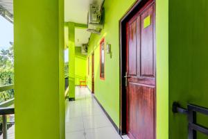 an empty hallway with a red door and green walls at Hotel O Cahyo Kost 1 in Semarang