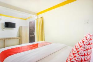 a bedroom with a bed and a tv on the wall at Hotel O Wisma Kuta Karang in Lhokseumawe