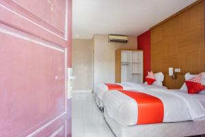 a bedroom with two beds with red and white at Hotel O Wisma Kuta Karang in Lhokseumawe