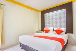 a bedroom with a large bed with red pillows at Hotel O Wisma Kuta Karang in Lhokseumawe