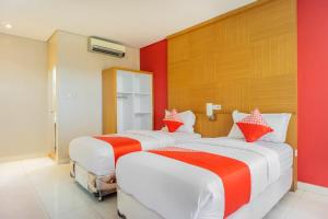 two beds in a hotel room with red walls at Hotel O Wisma Kuta Karang in Lhokseumawe +41 photos