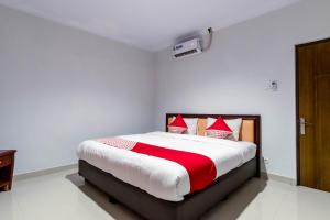 a bedroom with a large bed with red and white pillows at Hotel O Helvetia Residence in Medan