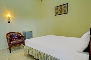 a bedroom with a white bed and a chair at Capital O 91806 Hotel Batu Suli in Palangkaraya