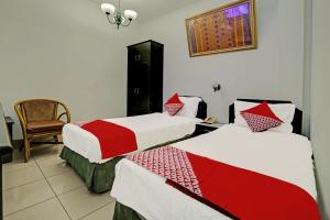 a room with two beds with red and white sheets at Hotel O Wisma Bari in Palembang