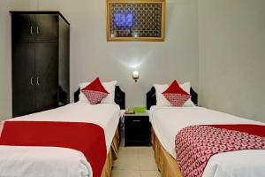 two beds in a room with red and white sheets at Hotel O Wisma Bari in Palembang +36 photos