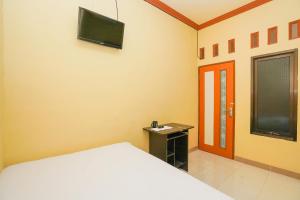 a bedroom with a bed and a television on the wall at OYO Life 2619 Kost Keluarga Cemara in Gresik