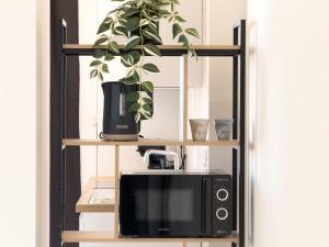 eine schwarze Mikrowelle auf einem Regal mit einer Pflanze in der Unterkunft Casa A'mar in Giardini-Naxos