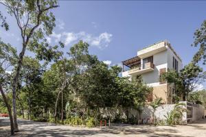 een wit gebouw met bomen ervoor bij Charming Tulum Getaway in Prime Location in Tulum
