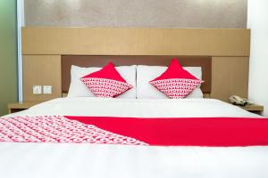 ein Bett mit roten und weißen Kissen darauf in der Unterkunft Capital O 664 Romance Hotel in Nagoya