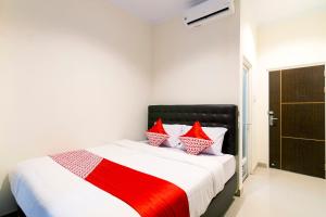 ein Schlafzimmer mit einem Bett mit roten und weißen Kissen in der Unterkunft OYO 1431 Travel-inn in Yogyakarta