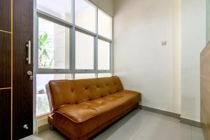 ein braunes Ledersofa in einem Zimmer mit Fenster in der Unterkunft OYO 1431 Travel-inn in Yogyakarta + 19 Fotos