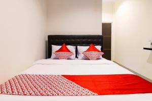 Bett mit roter und weißer Bettwäsche und Kissen in der Unterkunft OYO 1431 Travel-inn in Yogyakarta