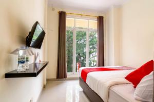 ein Schlafzimmer mit einem Bett, einem Fernseher und einem Fenster in der Unterkunft OYO 1431 Travel-inn in Yogyakarta