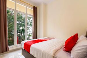 ein Schlafzimmer mit einem Bett mit roten Kissen und einem Fenster in der Unterkunft OYO 1431 Travel-inn in Yogyakarta