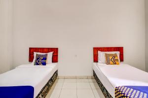 two beds sitting next to each other in a room at Hotel O Al-ghani 2 Syariah in Padang