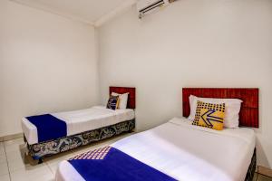two beds in a small room withthritisthritislictslictslicts at Hotel O Al-ghani 2 Syariah in Padang