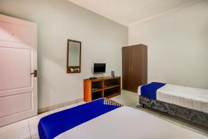 a hotel room with two beds and a television at Hotel O Al-ghani 2 Syariah in Padang