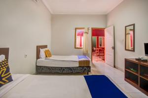 a bedroom with two beds and a tv and a door at Hotel O Al-ghani 2 Syariah in Padang