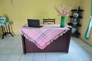 メダンにあるHotel O Ani Nur Homestay Syariahのピンクのテーブルクロスとノートパソコンが備わるテーブル