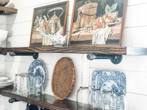 a shelf with plates and pictures on a wall at Charming Cottage w KING Bed 1m To Downtown in Columbia