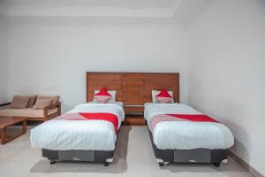 two twin beds in a room with a couch at Hotel O Bunga Karang Hotel in Bekasi