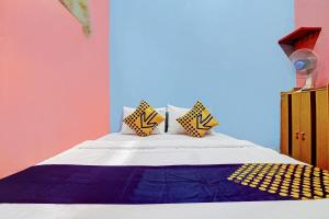 a bed with yellow and blue pillows on it at OYO 90268 Aliyah Syariah in Jakarta