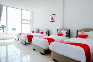een kamer met vier bedden met rode en witte lakens bij Hotel O Batu near Jatim Park formerly Villa Bukit Panderman Residence in Tlekung