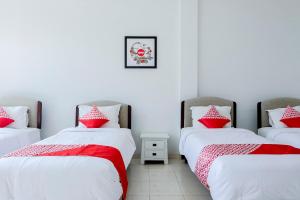2 bedden in een kamer met rode en witte kussens bij Hotel O Batu near Jatim Park formerly Villa Bukit Panderman Residence in Tlekung