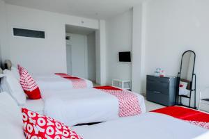 een kamer met 3 bedden met rode en witte kussens bij Hotel O Batu near Jatim Park formerly Villa Bukit Panderman Residence in Tlekung +24 foto's