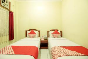 two beds in a room with red and white sheets at Hotel O Alfa Guest House in Jakarta